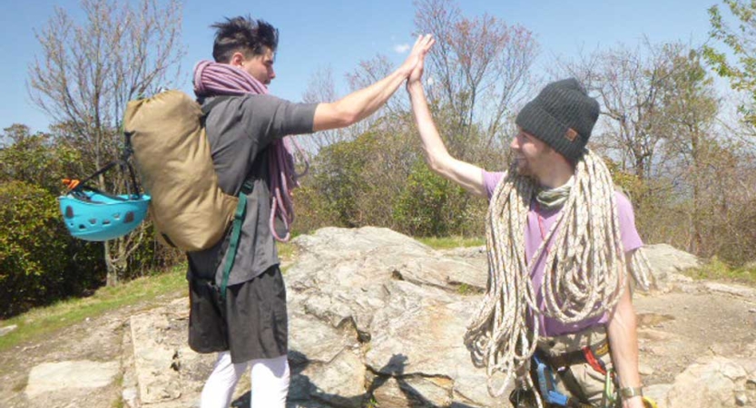 two gap year students wearing climbing gear high five